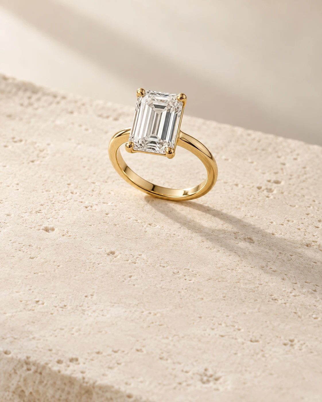 Anillo solitario de oro amarillo con una piedra rectangular sobre caliza marfil